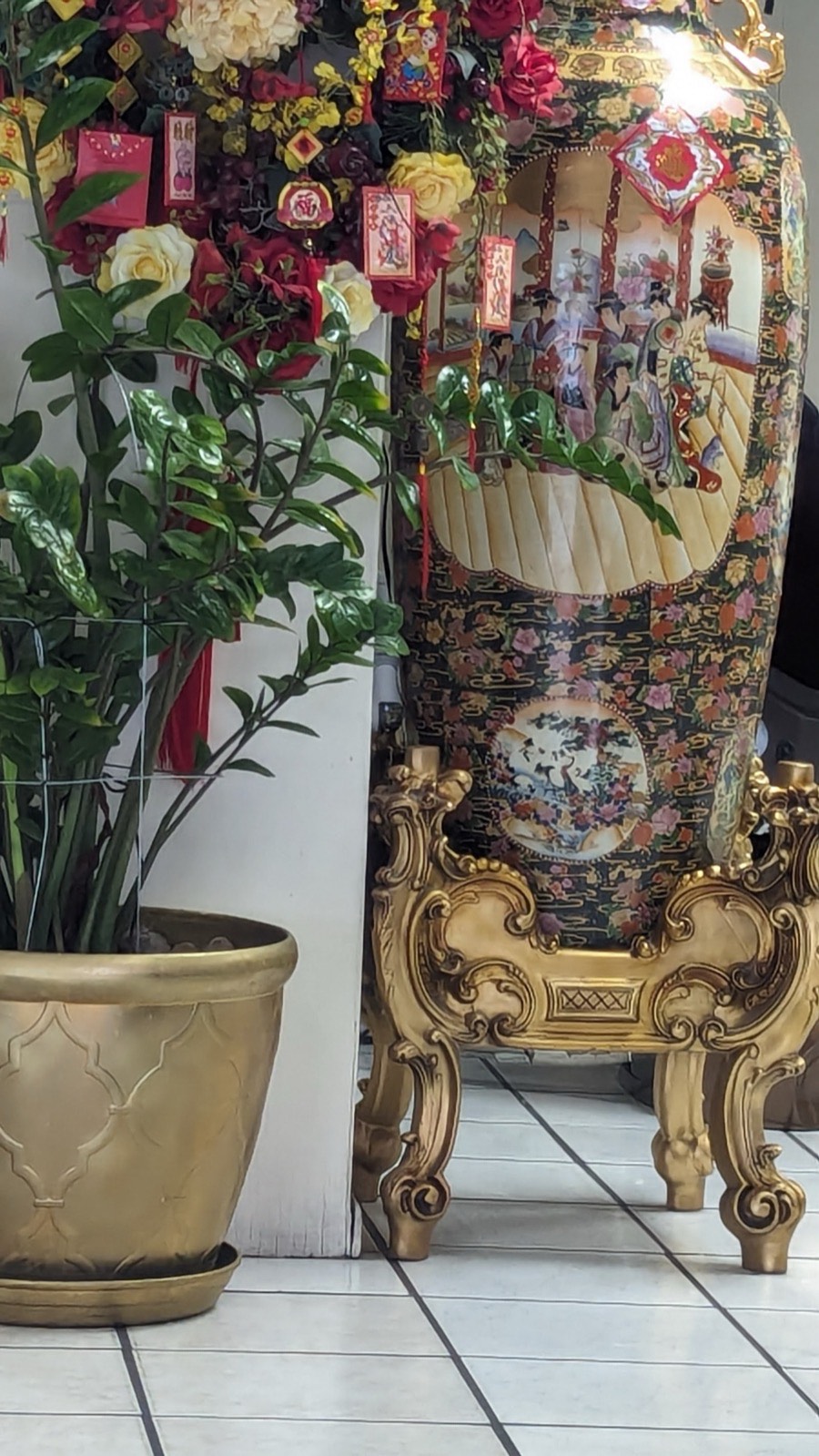 A tall painted vase and greenery in a corner of the salon